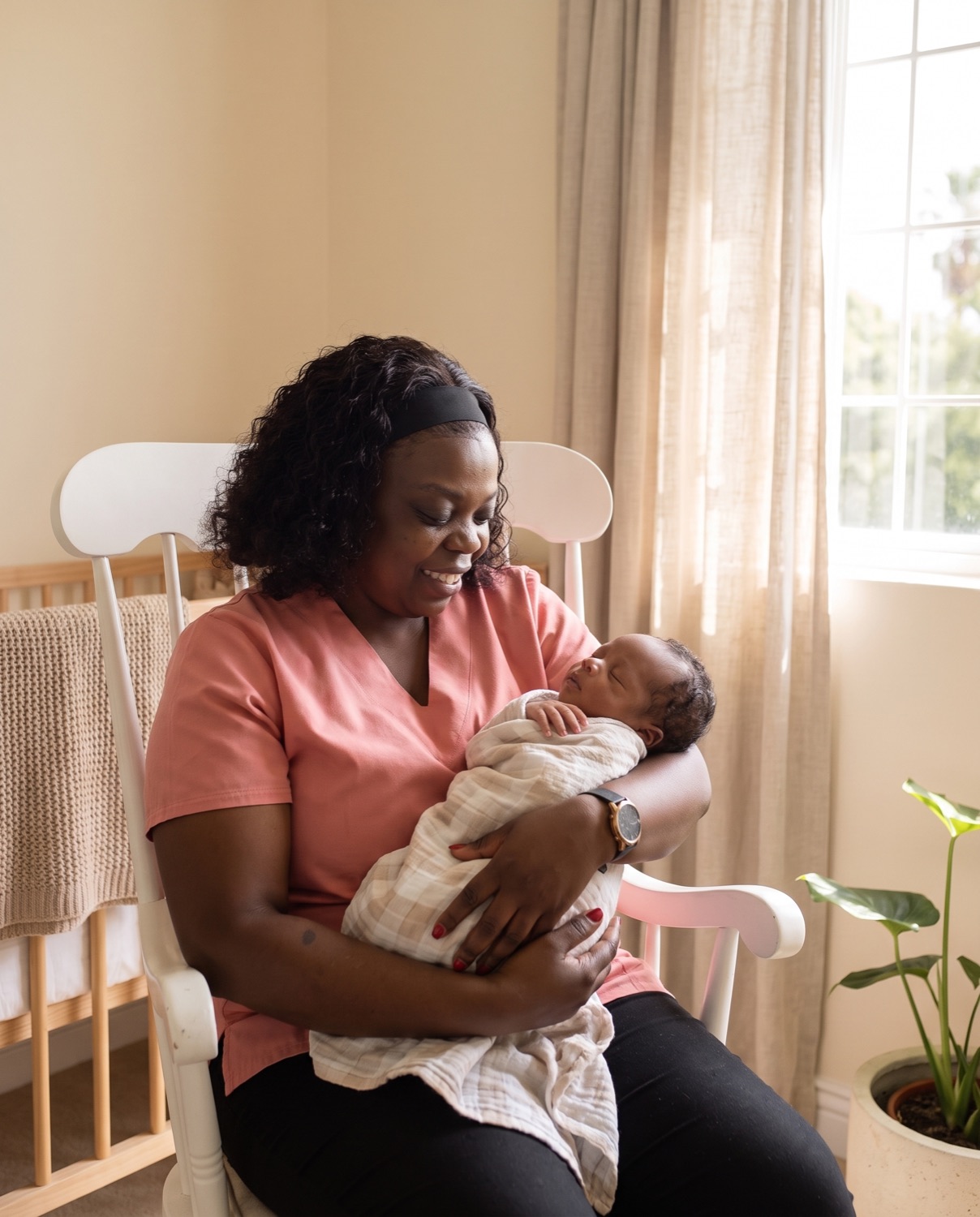 Yvonne in a rocking chair cradling a sleeping newborn